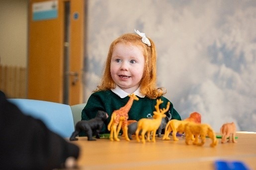 A young pupil playing with toy animals at a classroom table