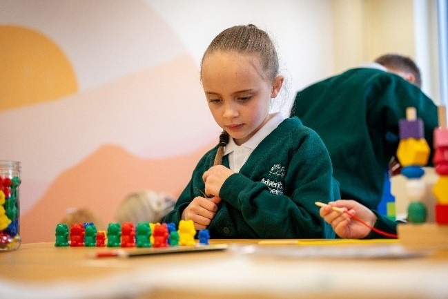A pupil concentrating on a counting activity in a classroom